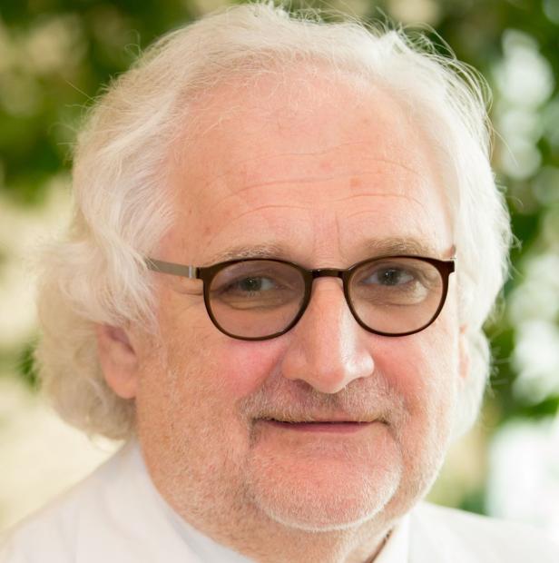 Porträt eines älteren Mannes mit Brille und weißem Haar.