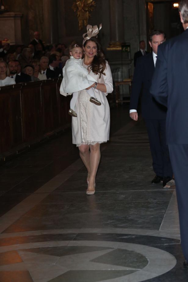 Eine Frau mit Hut trägt ein Kind in einer Kirche.