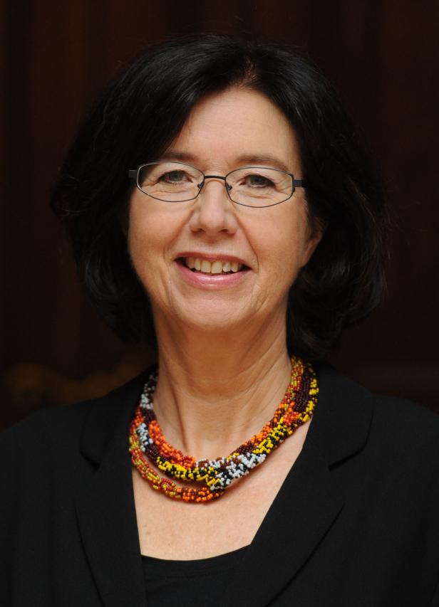 Eine lächelnde Frau mit Brille und einer bunten Halskette.