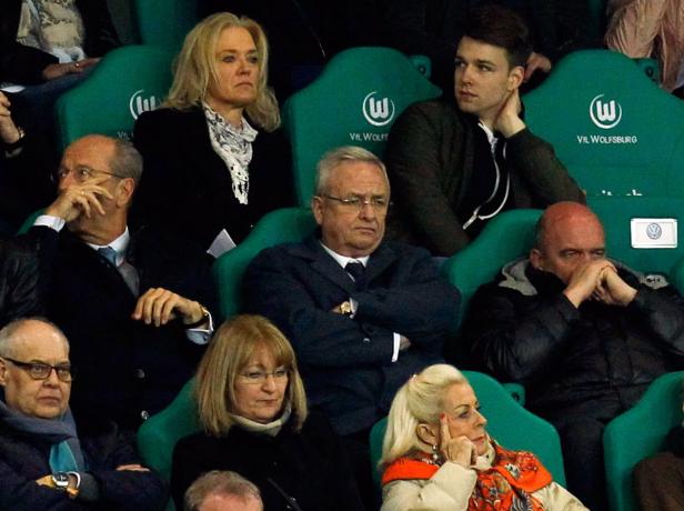 Mehrere Personen sitzen auf grünen Sitzen mit dem VW-Logo.