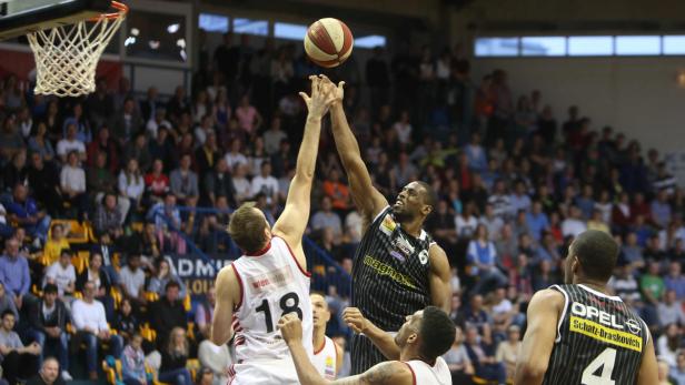 Zwei Basketballspieler kämpfen um den Ball vor einer Zuschauermenge.