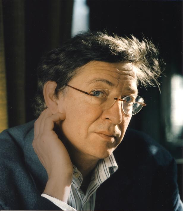 Ein Mann mit Brille und Anzug hält seine Hand an sein Gesicht.