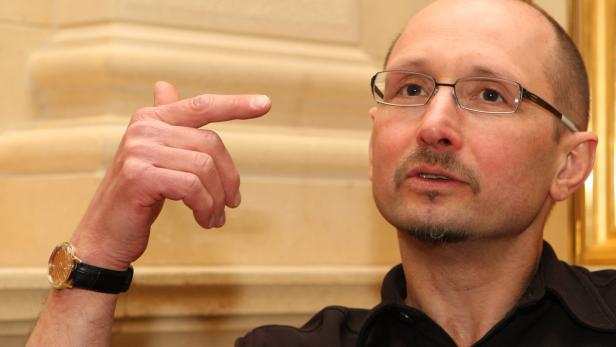 Ein Mann mit Brille und Uhr gestikuliert mit dem Finger.
