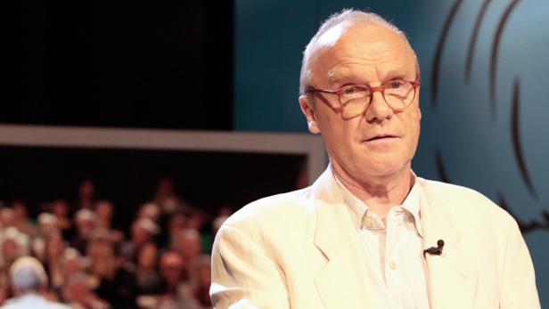 Ein Mann mit Brille und hellem Sakko spricht vor einem Publikum.