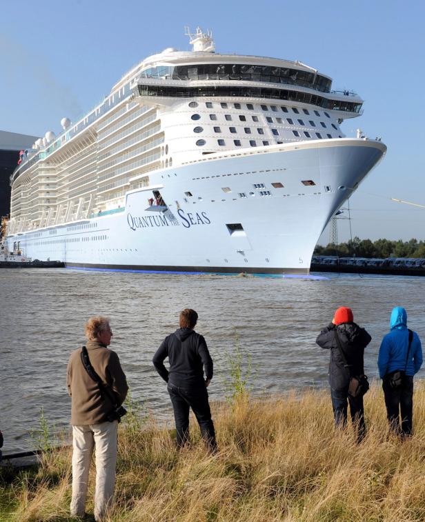 Die „Quantum of the Seas“ fährt auf einem Fluss, beobachtet von mehreren Personen.