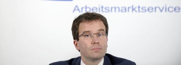 AMS-Chef Kopf Ein Mann mit Brille vor dem Schriftzug Arbeitsmarktservice.