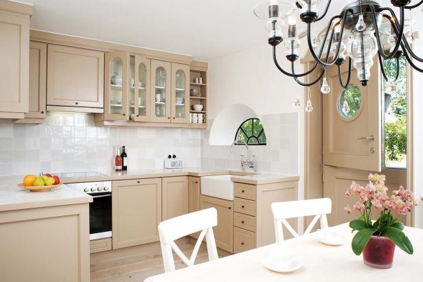 Eine helle Küche mit beigen Schränken und einem Esstisch mit Orchideen.