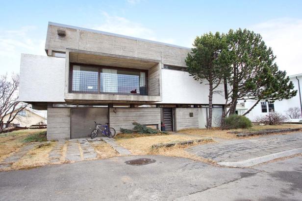 Ein modernes Wohnhaus mit Betonfassade und einem Fahrrad davor.