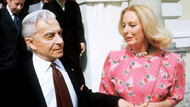 25. Todestag: Herbert und Eliette von Karajan 1986 Ein älterer Mann im Anzug und eine blonde Frau in einem rosa Kleid unterhalten sich.