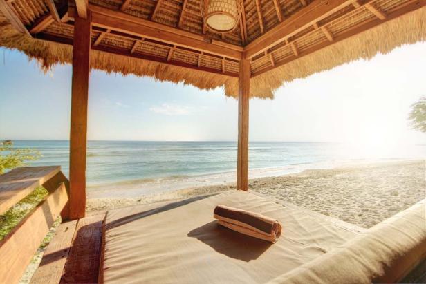 Ein Strand-Pavillon mit Blick auf das Meer und einem zusammengerollten Handtuch auf der Liege.