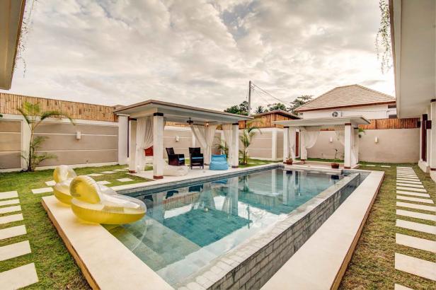 Ein Swimmingpool mit Pavillons und aufblasbaren Schwimmtieren in einem Garten.