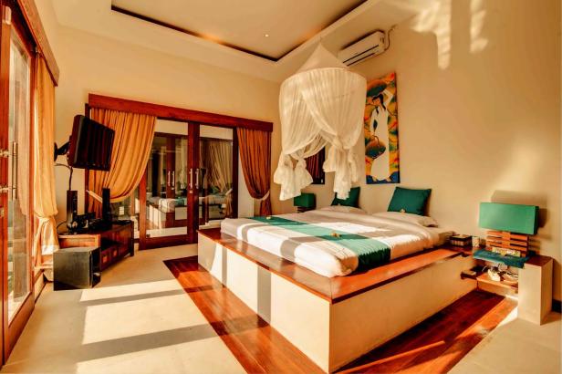 Ein helles Schlafzimmer mit einem Himmelbett und einem Gemälde an der Wand.