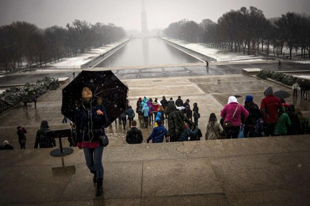 Eine Frau mit Regenschirm geht im Winter die Stufen am Lincoln Memorial hinunter.