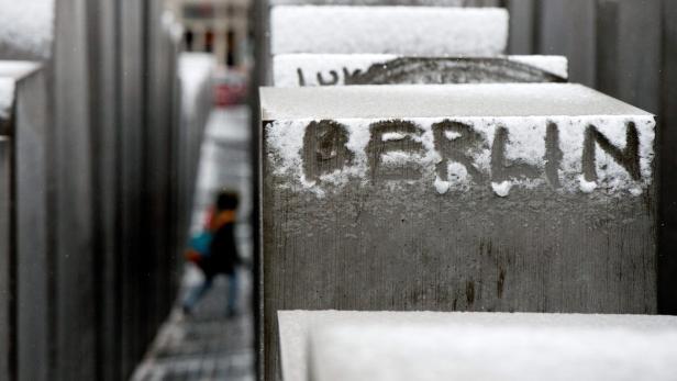 Auf einem Stein des Holocaust-Mahnmals in Berlin steht mit Schnee geschrieben das Wort „Berlin“.