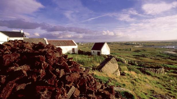Häuser und eine Torfmiete in einer ländlichen irischen Landschaft.