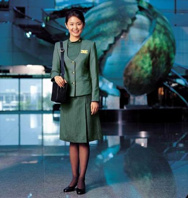 Eine lächelnde Flugbegleiterin in Uniform posiert in einem Flughafenterminal.