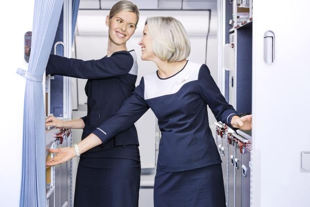 Zwei Stewardessen in Uniform stehen in der Bordküche eines Flugzeugs.