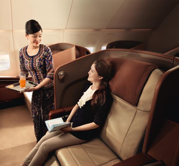 Eine Flugbegleiterin serviert einer Passagierin in der Business Class ein Getränk.