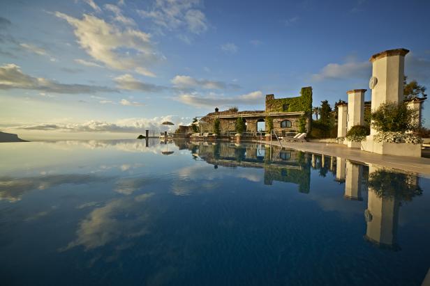Ein Infinity-Pool spiegelt den Himmel und die Architektur eines Resorts wider.