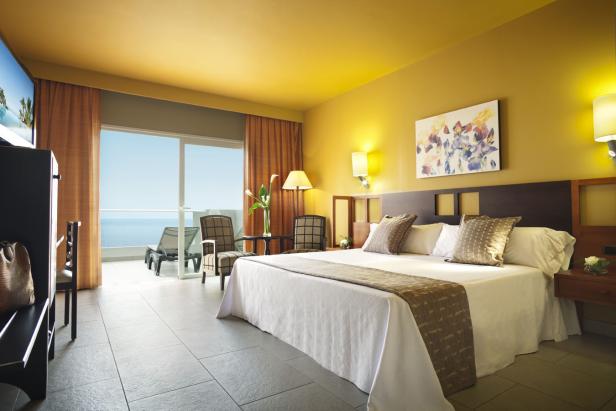 Ein Hotelzimmer mit Meerblick und einem Doppelbett mit weißer Bettwäsche.