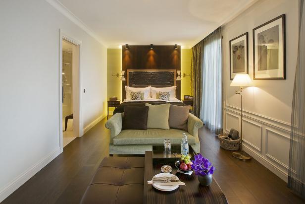 Ein Hotelzimmer mit einem Bett, einem Sofa und einem Tisch mit Obst und Blumen.