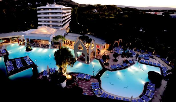 Ein Hotelresort mit mehreren Pools und Liegestühlen bei Dämmerung.