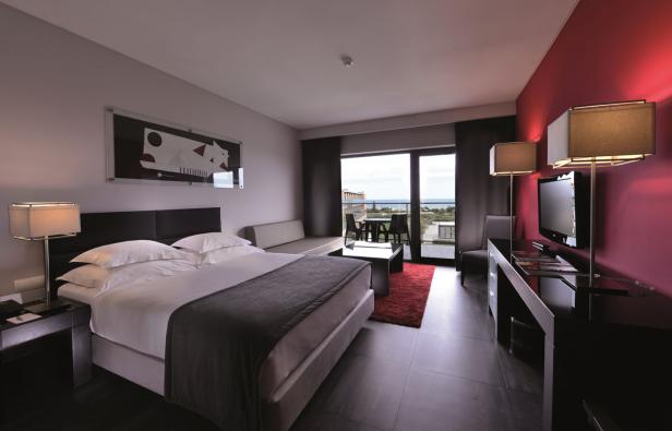 Ein modernes Hotelzimmer mit Doppelbett und Blick auf das Meer.