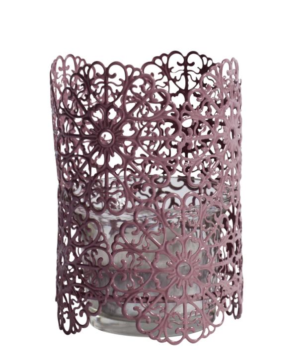 Ein Teelichthalter aus rosa Metall mit einem filigranen, floralen Muster umgibt ein Glaswindlicht.