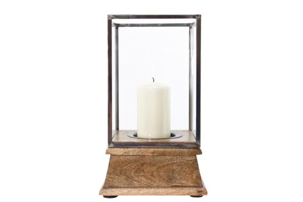 Eine weiße Kerze in einem dekorativen Kerzenhalter aus Holz und Glas.