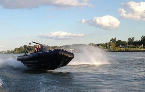 Ein schnelles, schwarzes Motorboot rast über das Wasser.
