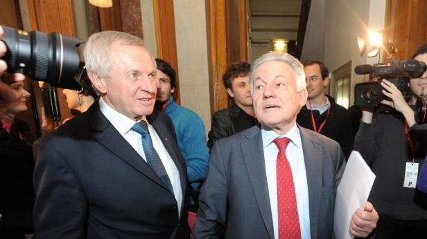 Zwei Männer in Anzügen stehen im Rampenlicht der Kameras.