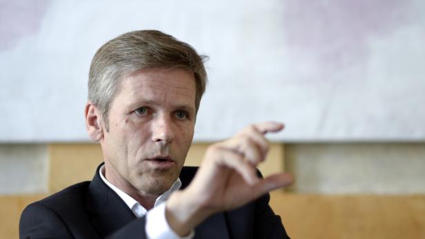 Ein Mann im Anzug gestikuliert mit der Hand.