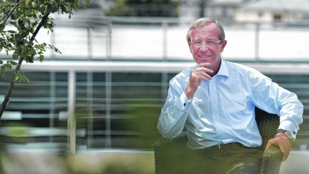 Ein Mann mit Brille sitzt draußen und denkt nach.