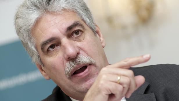 Ein Mann mit grauem Haar und Schnurrbart gestikuliert mit dem Finger.