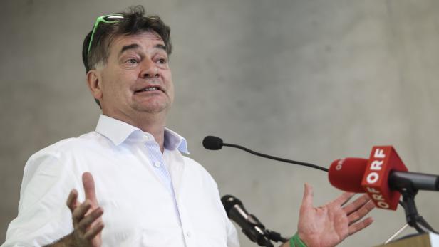 Ein Mann spricht an einem Rednerpult mit Mikrofonen.