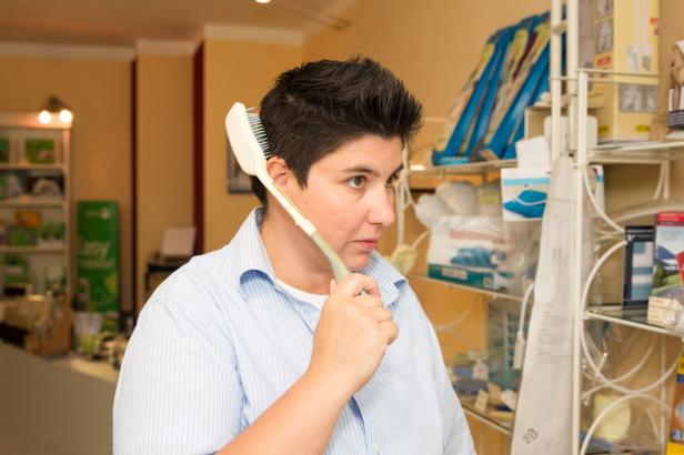 Eine Frau hält eine Haarbürste an ihr Ohr wie ein Telefon.