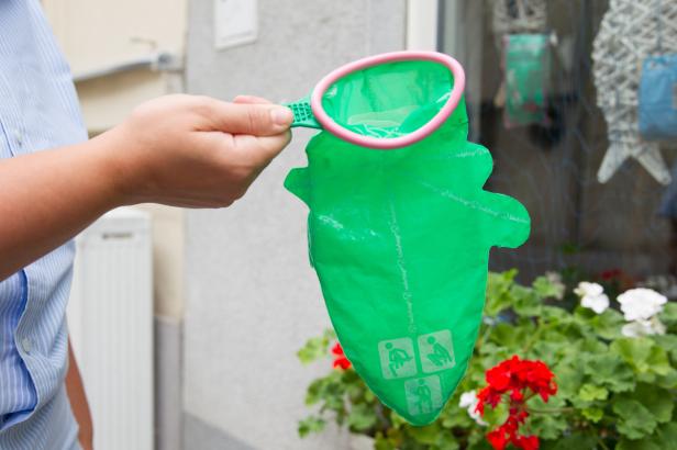 Eine Hand hält einen grünen „Ladybag“-Kotbeutel für Hunde.