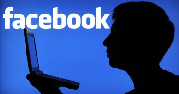 Die Silhouette einer Person mit einem Laptop vor dem Facebook-Logo.
