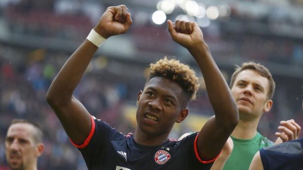 David Alaba jubelt mit erhobenen Armen, während Manuel Neuer im Hintergrund steht.