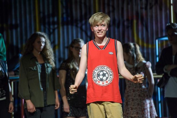 Ein junger Mann in einem roten Trikot mit dem Aufdruck „FC Rot Weiss Gagran“ lächelt.