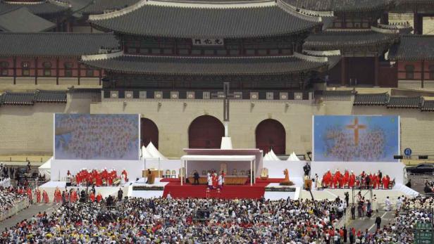Eine große Menschenmenge versammelt sich vor einem traditionellen koreanischen Gebäude mit einem Kreuz.