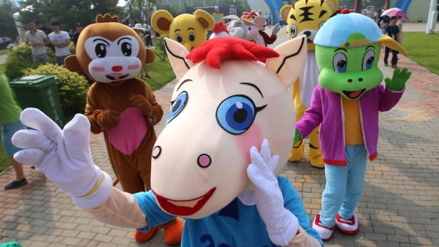 Eine Gruppe von Maskottchen steht im Freien und winkt.