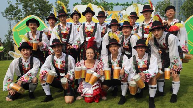 Eine Gruppe von Menschen in Tracht hält Bierkrüge in der Hand.