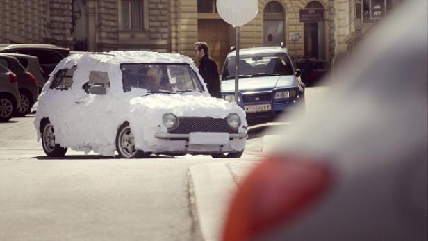 NÖM - Markenkampagne 2015 - TV-Spot Bild 4 Ein mit Papier beklebtes Auto steht auf einer Straße.