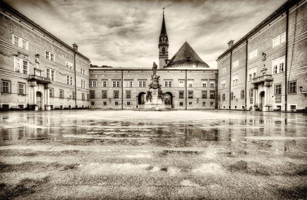 Der Residenzplatz in Salzburg mit nassen Pflastersteinen und Blick auf den Dom.