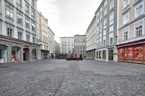 Ein menschenleerer Platz in Salzburg mit Kopfsteinpflaster und historischen Gebäuden.