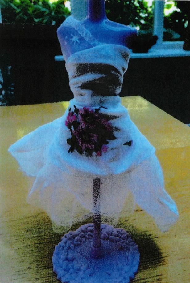 Eine Schneiderpuppe mit einem weißen Kleid und Blumenapplikationen.