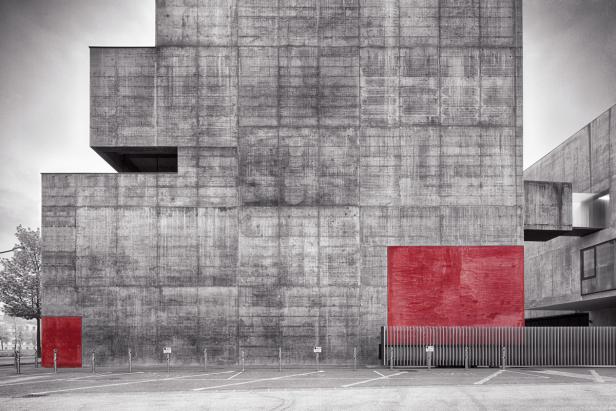 Ein Gebäude aus grauem Beton mit einem roten Element und einer roten Tür an der Seite.