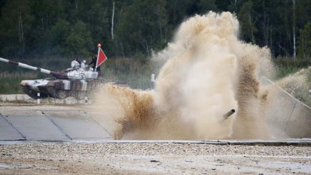 Ein Panzer durchfährt ein Wasserhindernis, wobei viel Wasser aufspritzt.