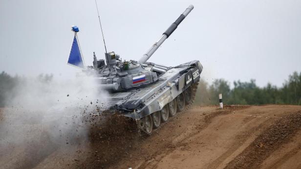 Ein russischer Panzer fährt über eine Sandpiste und wirbelt Staub auf.